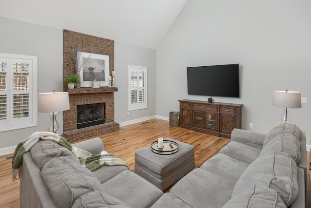 living room featuring high vaulted ceiling, a fireplace, and hardwood / wood-style flooring