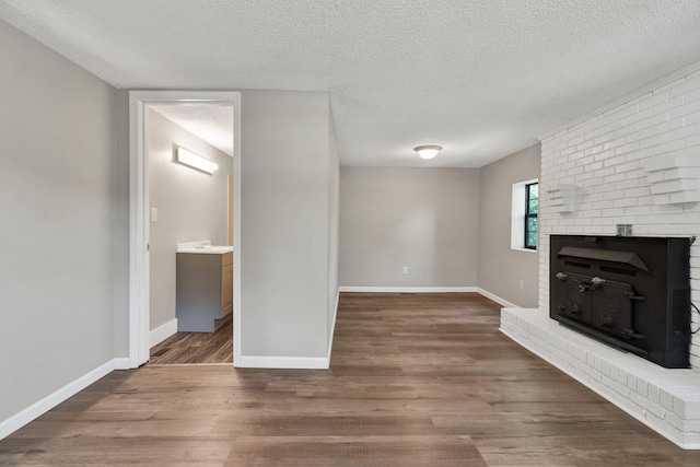 unfurnished living room with dark wood finished floors, a textured ceiling, and baseboards