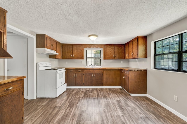 kitchen with dark wood-style floors, white range with electric stovetop, brown cabinets, under cabinet range hood, and baseboards