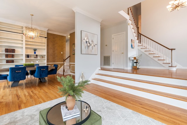 entrance foyer featuring a chandelier, crown molding, and wood-type flooring