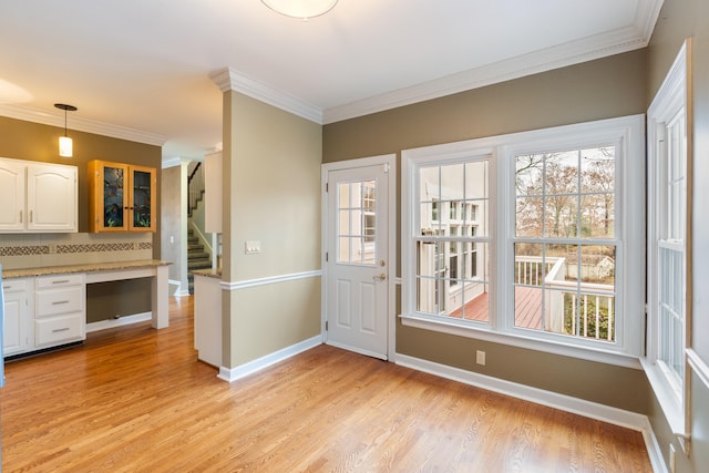 interior space featuring white cabinets, backsplash, decorative light fixtures, and ornamental molding