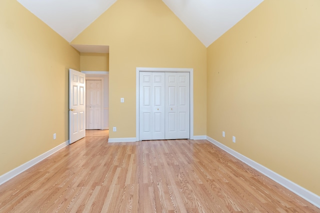 unfurnished bedroom featuring light hardwood / wood-style floors, high vaulted ceiling, and a closet