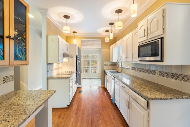 kitchen featuring white cabinetry, sink, stainless steel appliances, pendant lighting, and decorative backsplash