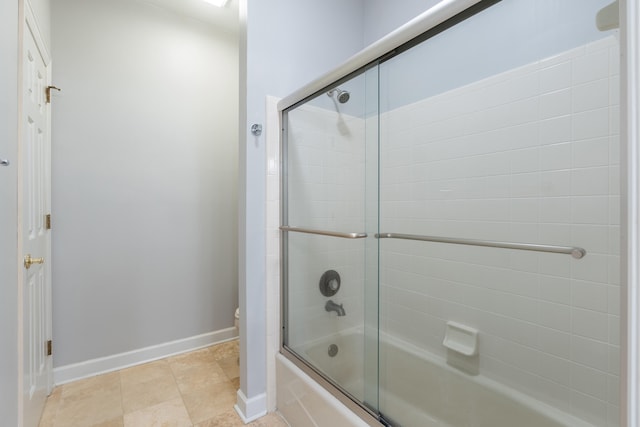 bathroom with toilet and shower / bath combination with glass door