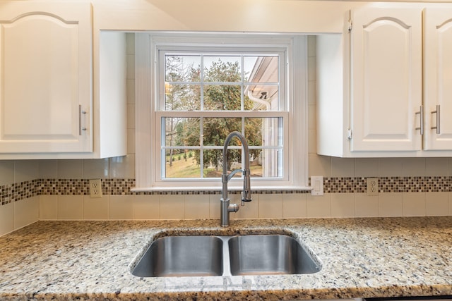 kitchen with decorative backsplash, sink, white cabinets, and light stone countertops