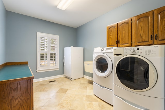 clothes washing area featuring cabinets and washing machine and clothes dryer