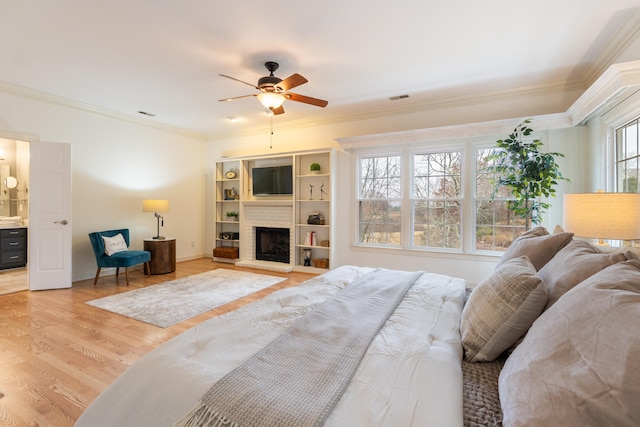 bedroom with a brick fireplace, ceiling fan, light hardwood / wood-style floors, and ornamental molding