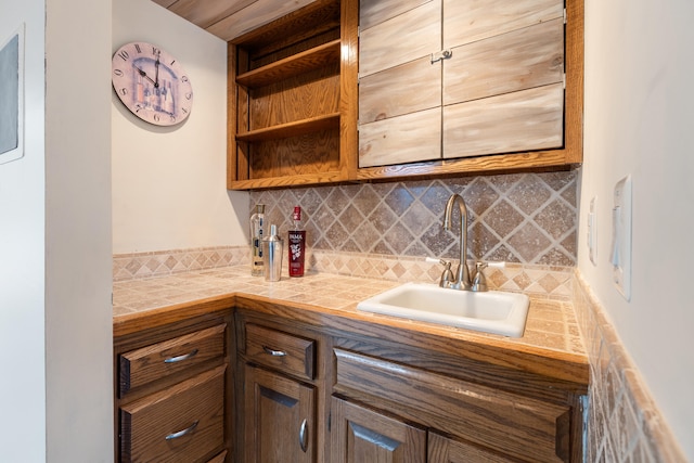 kitchen with tile counters, decorative backsplash, and sink