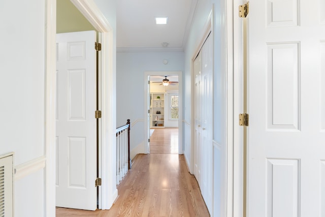 hall with light wood-type flooring and crown molding