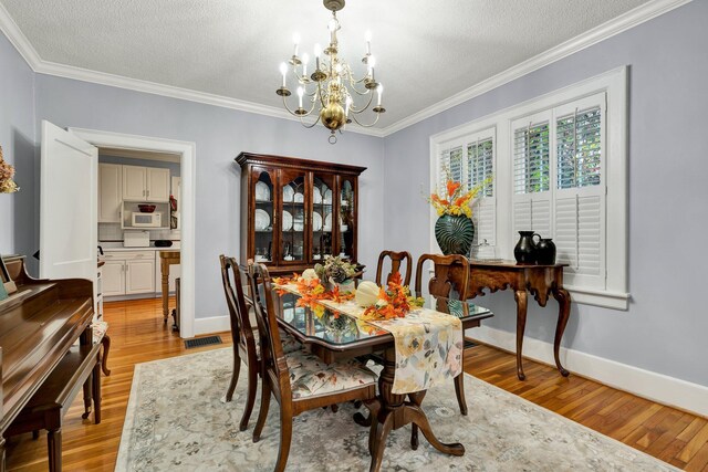 431 Highland Ave NW, Cleveland, TN 37311 - dining space with a chandelier, light wood-style flooring, ornamental molding, and a textured ceiling