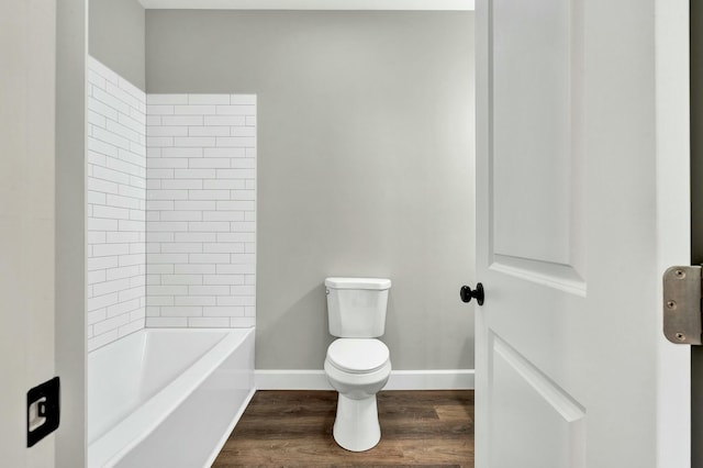 bathroom with hardwood / wood-style floors, toilet, and a tub