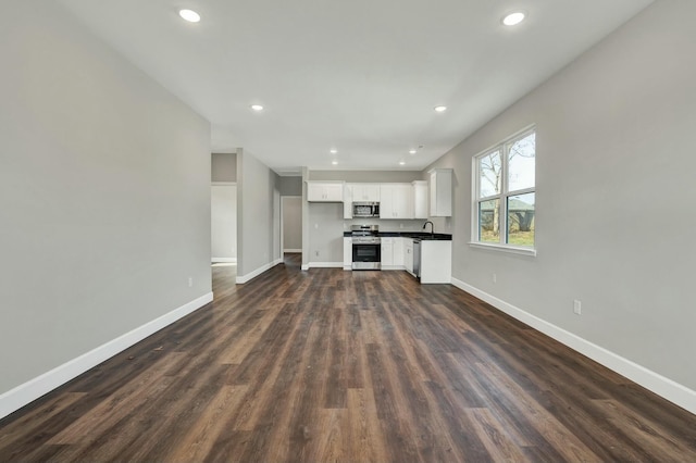 unfurnished living room featuring sink and dark wood-type flooring