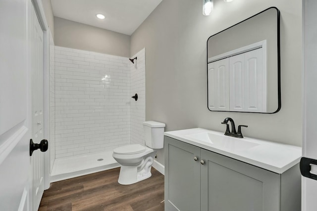 bathroom featuring hardwood / wood-style floors, vanity, a tile shower, and toilet