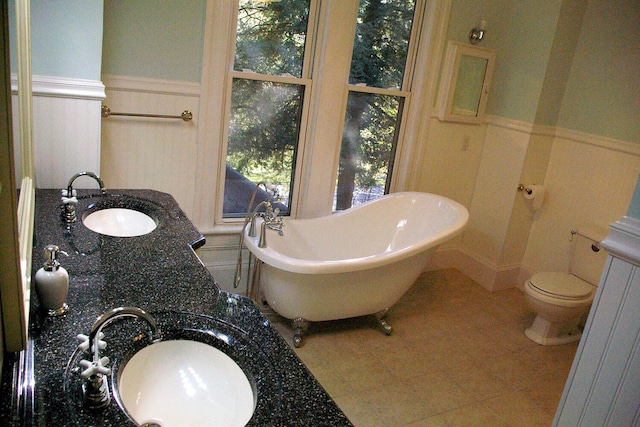 full bathroom featuring a soaking tub, a sink, and wainscoting