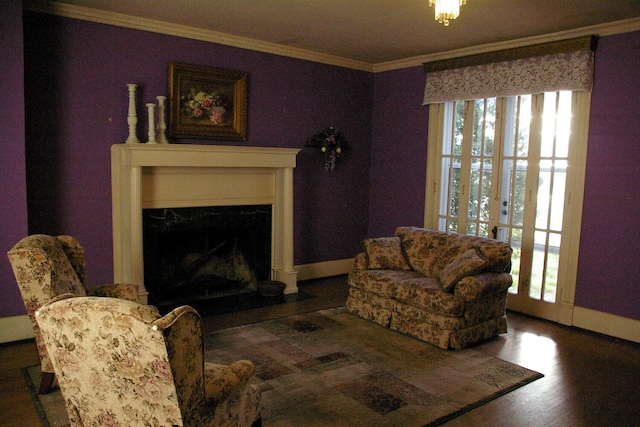 living area featuring a fireplace with flush hearth, ornamental molding, baseboards, and wood finished floors