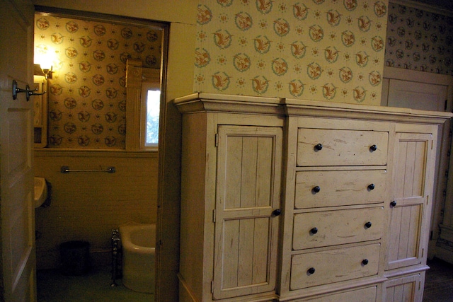 bathroom featuring wainscoting and wallpapered walls