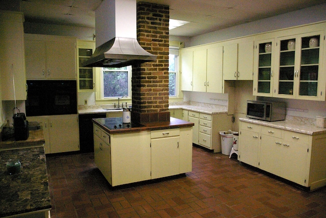 kitchen featuring island range hood, stainless steel microwave, a center island, oven, and black electric stovetop