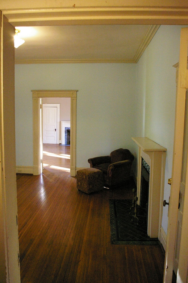 sitting room featuring a fireplace, crown molding, baseboards, and wood finished floors