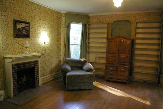 sitting room featuring ornamental molding, a brick fireplace, wood finished floors, and wallpapered walls