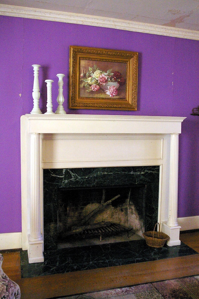 interior details with baseboards, a fireplace, ornamental molding, and wood finished floors