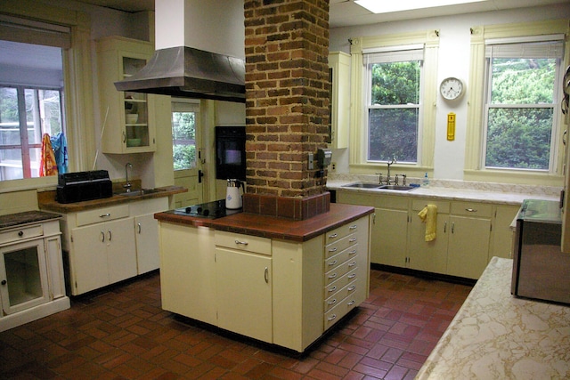 kitchen featuring black appliances, island range hood, brick floor, and a sink