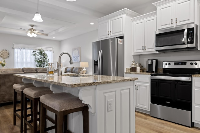 kitchen featuring appliances with stainless steel finishes, a kitchen island with sink, and white cabinets