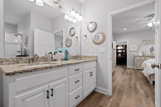 bathroom with vanity, hardwood / wood-style flooring, a shower with door, and ceiling fan