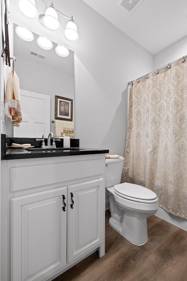 bathroom featuring wood-type flooring, toilet, and vanity