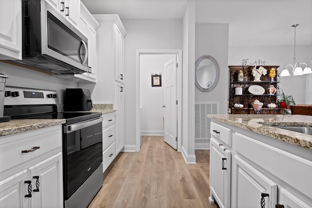 kitchen featuring white cabinetry, an inviting chandelier, decorative light fixtures, light hardwood / wood-style flooring, and appliances with stainless steel finishes