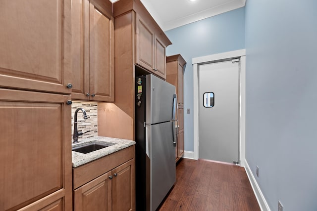 kitchen featuring stainless steel refrigerator, tasteful backsplash, sink, light stone countertops, and dark wood-type flooring