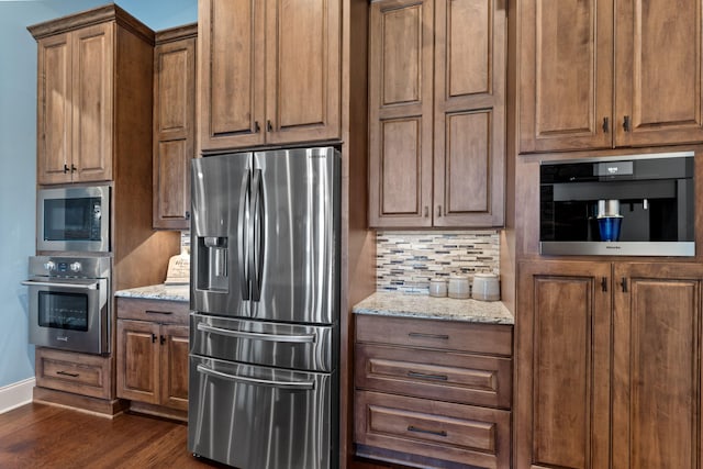 kitchen featuring decorative backsplash, light stone countertops, dark hardwood / wood-style floors, and appliances with stainless steel finishes
