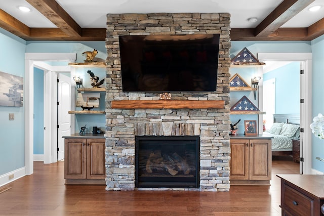 living room with beamed ceiling, a stone fireplace, and dark wood-type flooring