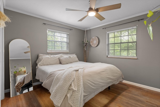 bedroom with multiple windows, wood finished floors, baseboards, and ornamental molding