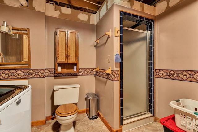 full bathroom featuring washer / clothes dryer, toilet, wainscoting, and a stall shower