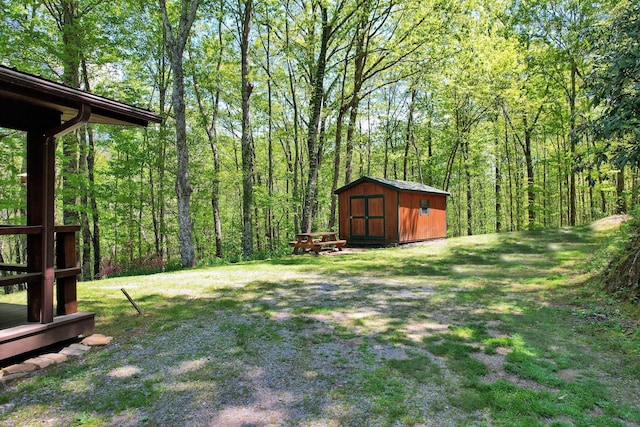 view of yard with a view of trees, an outbuilding, and a storage unit