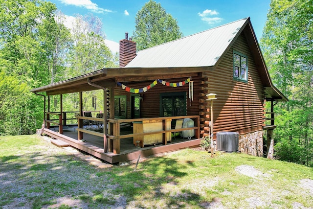 view of side of property with a deck, french doors, a chimney, log siding, and central air condition unit