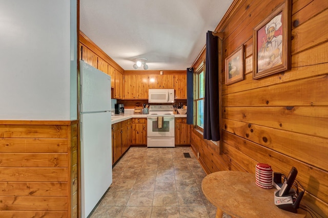 kitchen with light countertops, wooden walls, and white appliances