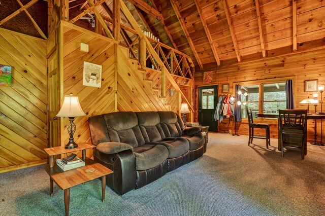 carpeted living room with wood walls, wooden ceiling, high vaulted ceiling, beamed ceiling, and stairs