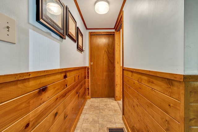 doorway featuring wooden walls, wainscoting, and visible vents