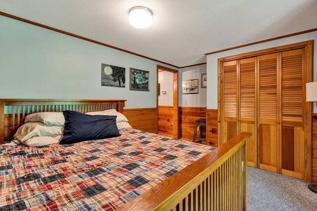 bedroom featuring crown molding, wood walls, carpet flooring, and a closet
