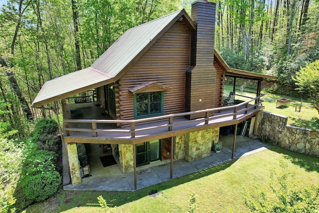 rear view of property featuring a yard, a chimney, and a patio area