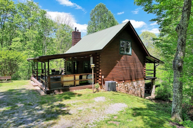 view of side of property with a lawn, log siding, a chimney, and cooling unit