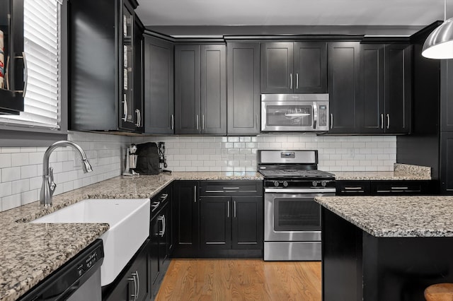 1422 Adams St, Chattanooga, TN 37408 - kitchen with appliances with stainless steel finishes, dark cabinets, light wood-style floors, a sink, and tasteful backsplash