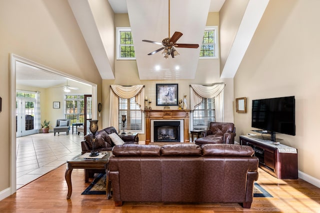 living room featuring ceiling fan, light hardwood / wood-style flooring, and a towering ceiling