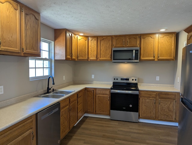 kitchen featuring dark hardwood / wood-style flooring, sink, stainless steel appliances, and a textured ceiling