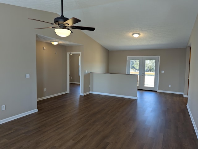 empty room with french doors, vaulted ceiling, dark wood-type flooring, and a textured ceiling