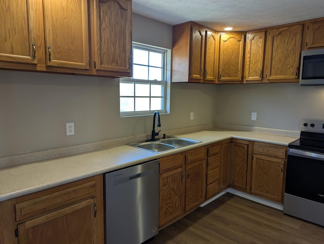 kitchen featuring appliances with stainless steel finishes, sink, a textured ceiling, and dark hardwood / wood-style floors