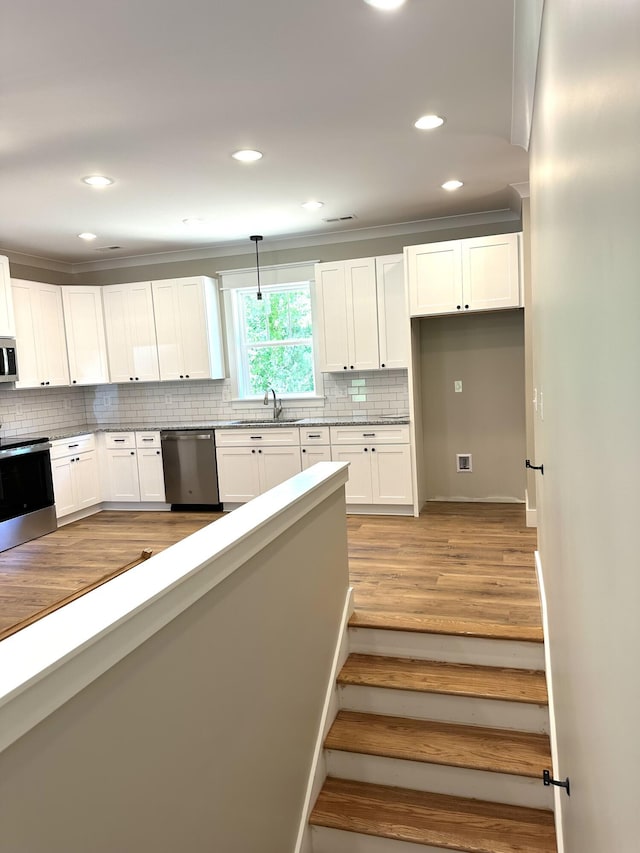 110 Dakota Dr NE, Cleveland, TN 37323 - kitchen with appliances with stainless steel finishes, light wood finished floors, tasteful backsplash, white cabinetry, and recessed lighting