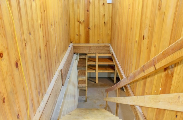 stairway featuring wood walls