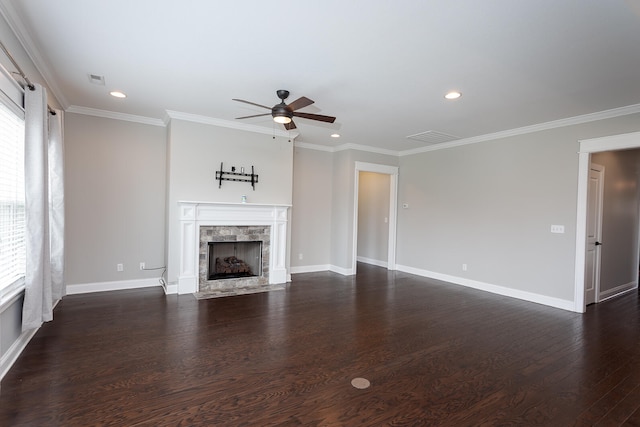 unfurnished living room featuring crown molding, ceiling fan, a stone fireplace, and dark wood-type flooring